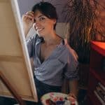 Creative woman painter smiling with palette in cozy art studio.