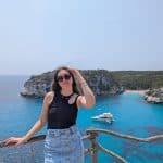 Beautiful woman at a scenic seaside location in summer, wearing sunglasses and trendy casual outfit.