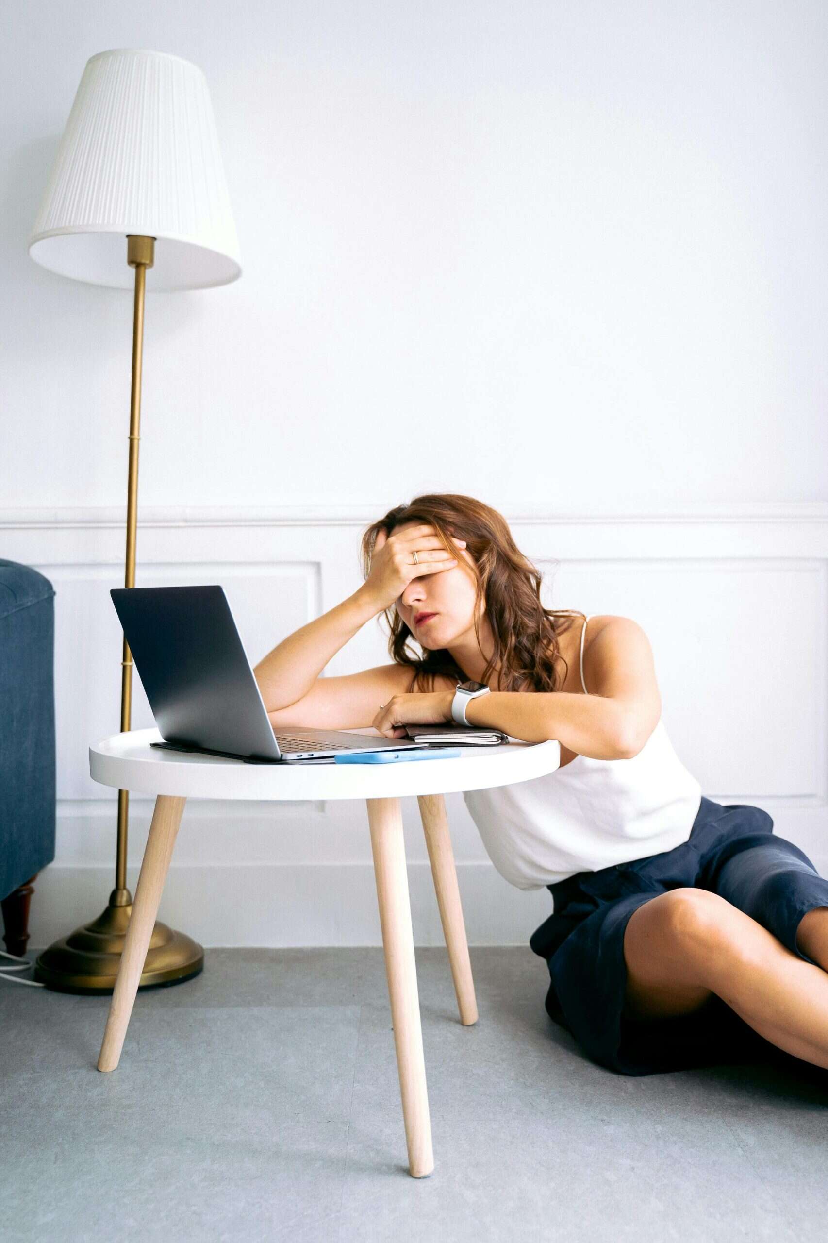 Stressed woman with headache resting on a table with laptop at home or office.